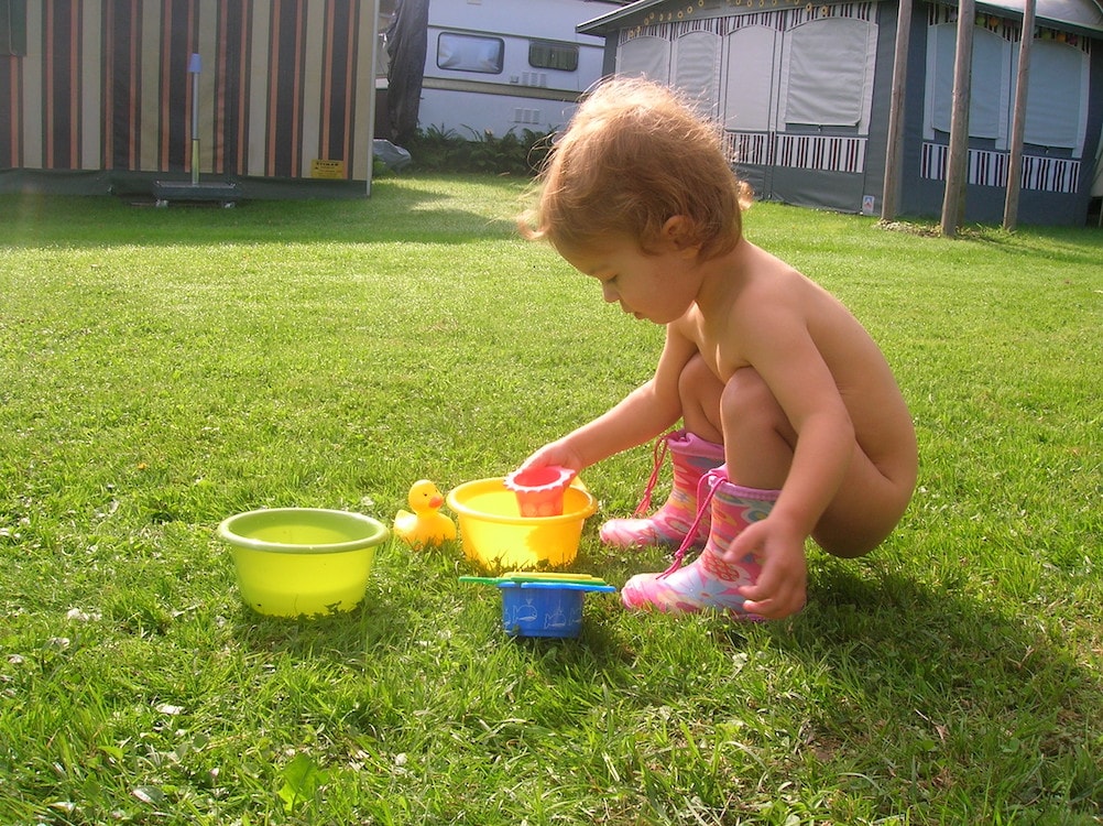 Praktische Philosophie: Ein Kleinkind spielt mit kleinen Schüsseln auf dem Rasen.
